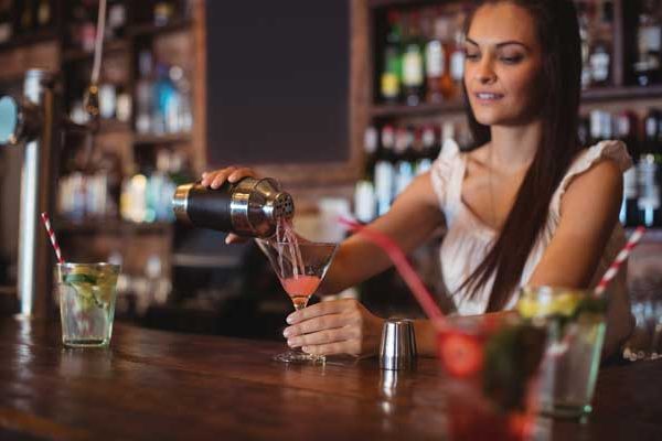 female-bartender-pouring-cocktail-drink-in-the-glass-600x400